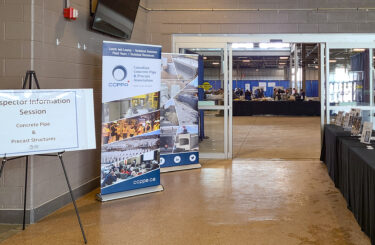 Entrance display for a CCPPA Inspector Information Session featuring signage, banners, and resource tables welcoming attendees to a technical seminar on concrete pipe and precast structures.